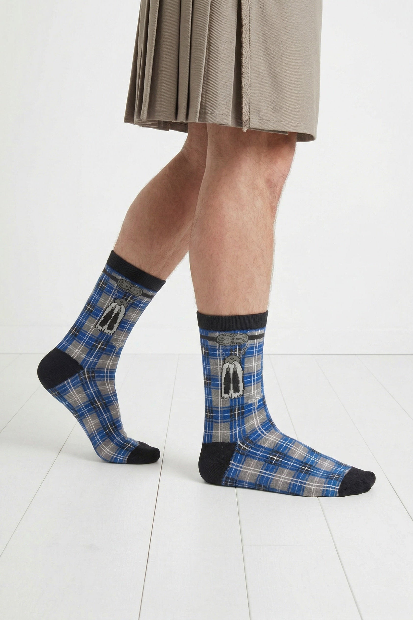 Person wearing blue tartan socks with black accents on a white floor.