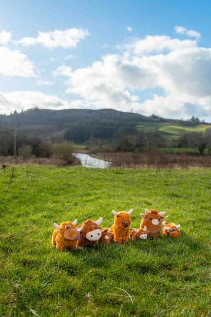 Plush toy animals on a grassy field with a scenic background.