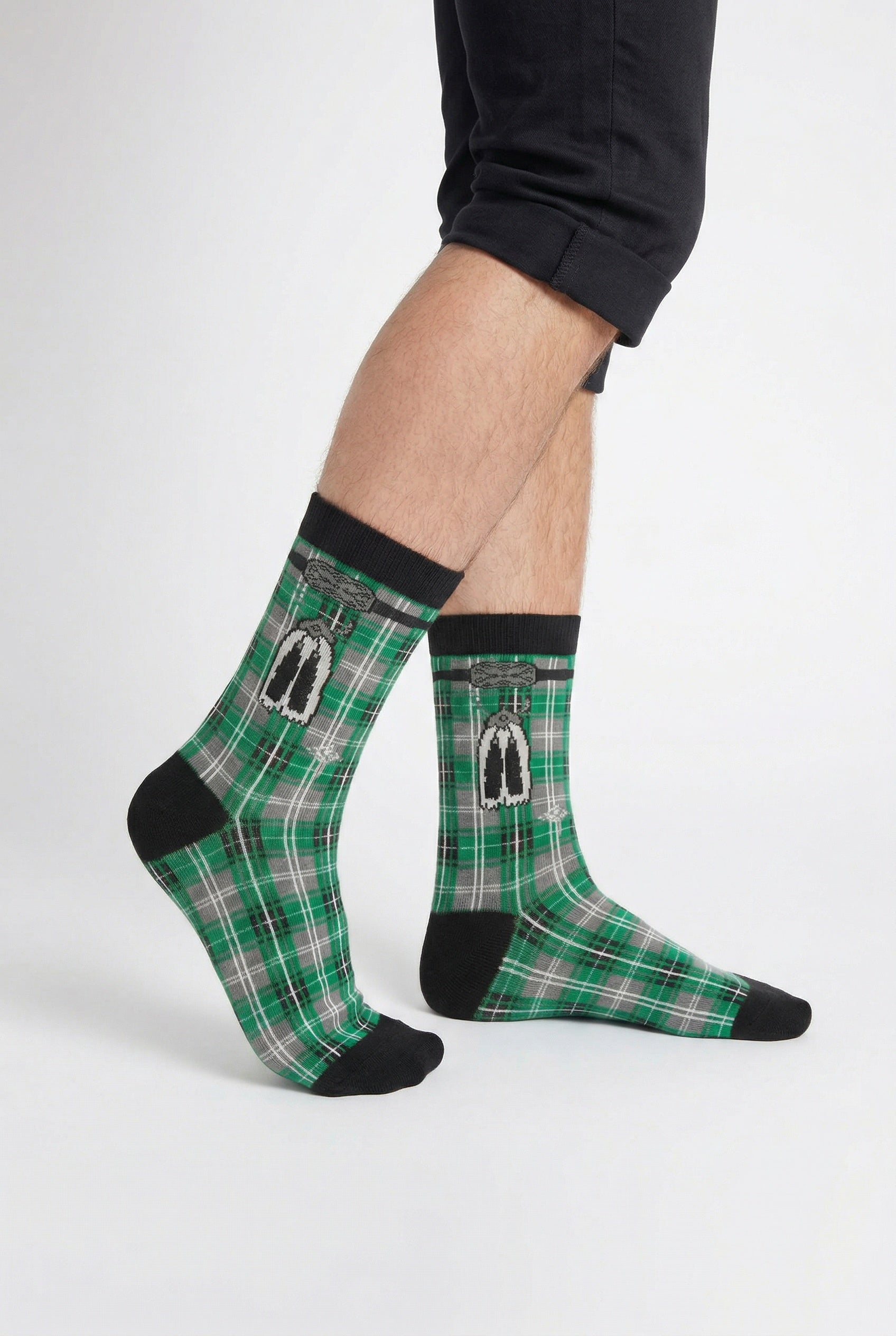 Green tartan socks with black accents worn by a person on a white background
