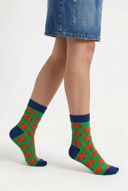Person wearing green socks with highland cow cartoon pattern on a white background