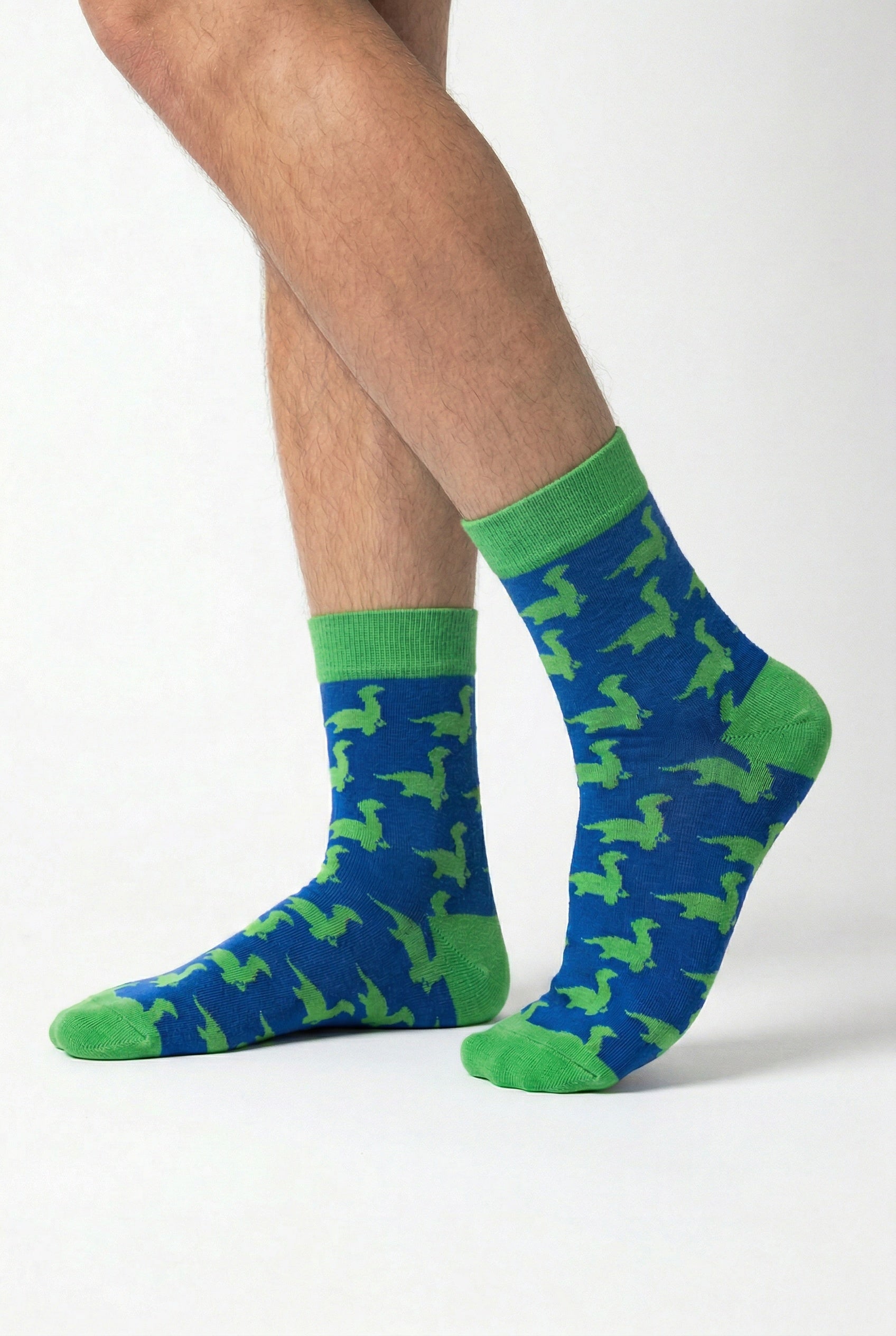 Blue socks with green loch ness monster pattern worn by a person on a white background