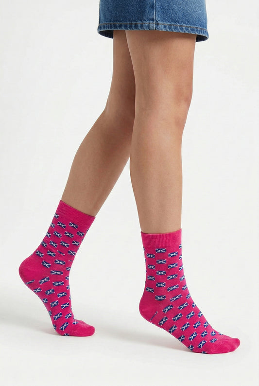 Person wearing pink socks with a scottish flag pattern on a white background