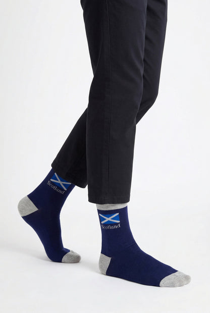 Person wearing navy socks with a scottish flag design and black pants on a white background
