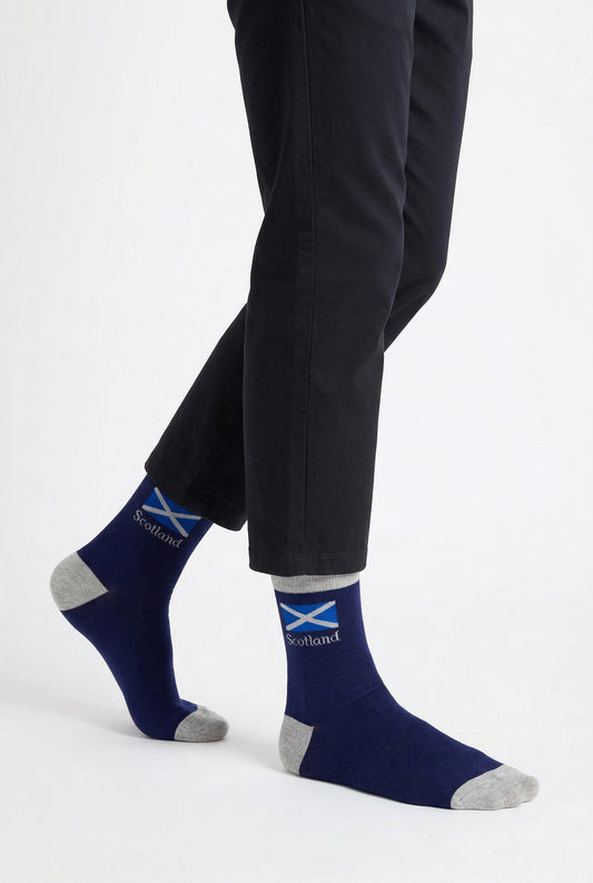Person wearing navy socks with a scottish flag design and black pants on a white background