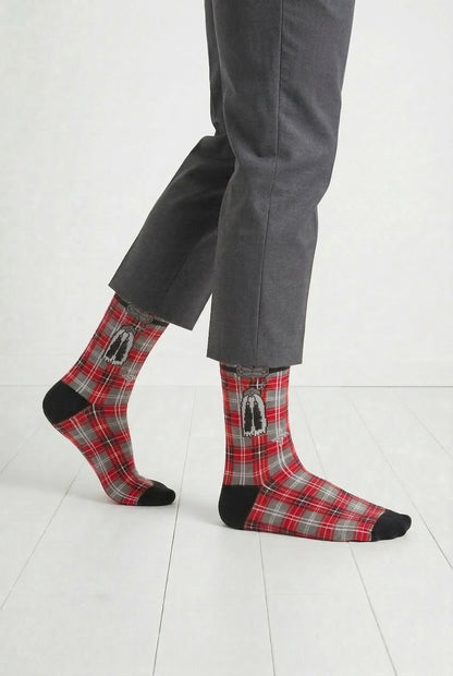 Red tartan socks with black accents worn by a person on a white floor.